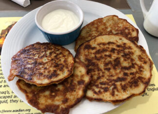 Acadian potato pancakes in Nova Scotia Acadian potato pancakes with sour cream in Nova Scotia.