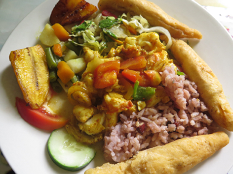 A plate of curried lobster with rice and peas, plantains, and festival on Winnifred Beach in Portland, Jamaica