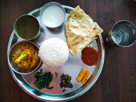Dal bhat, a thali-style dish in Kathmandu, Nepal, that places lentil dal, a curry, pickles, and a papad around a mound of rice. 