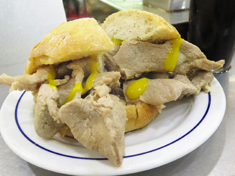 A pork bifana sandwich with yellow mustard from a cafe in Lisbon.
